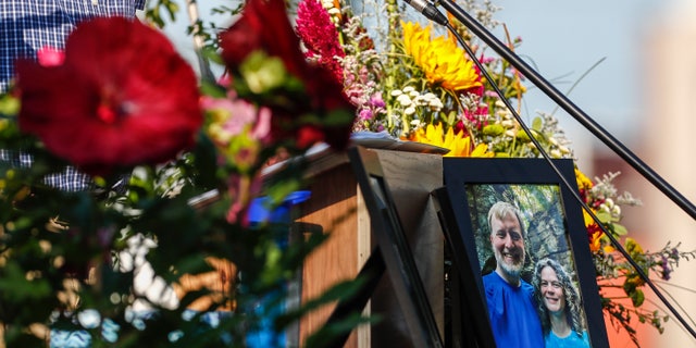 A photo of Tyler and Sarah Schmidt sits on a podium at the Celebration of Life event for Tyler, Sarah, and Lula Schmidt, held at Overman Park in Cedar Falls, Iowa. The Schmidts were shot and killed at Maquoketa Caves State Park on July 22.