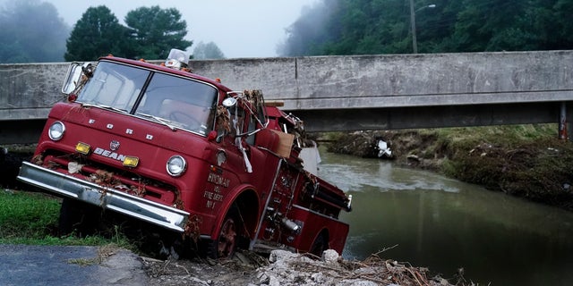 A fire truck is seen hanging over the edge of the water propped against a bridge in Hindman, Kentucky. Temperatures are soaring in a region of eastern Kentucky where people are shoveling out the wreckage of massive flooding.