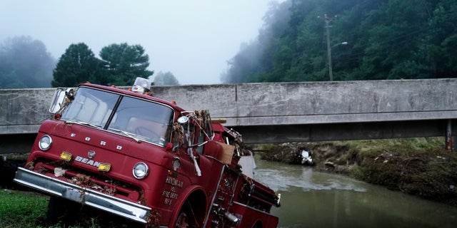 A fire truck is seen hanging over the edge of the water propped against a bridge in Hindman, Kentucky. Temperatures are soaring in a region of eastern Kentucky where people are shoveling out the wreckage of massive flooding.
