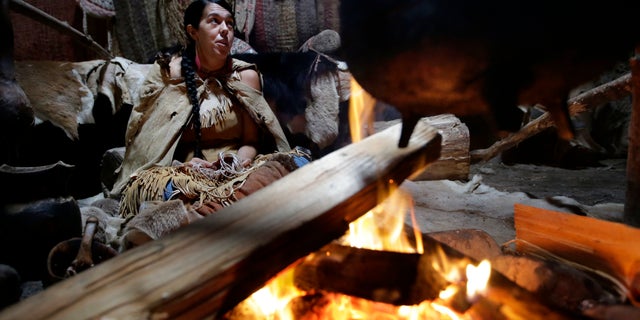 Mashpee Wampanoag Kerri Helme, of Fairhaven, Mass., uses plant fiber to weave a basket while sitting next to a fire on Nov. 15, 2018, at the Wampanoag Homesite at the Plimoth Patuxet Museums, in Plymouth, Mass. Native Americans in Massachusetts are calling for a boycott of a popular living history museum.