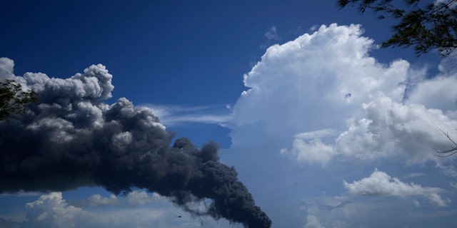 Una enorme columna de humo se eleva desde la base de superpetroleros de Matanzas, mientras los bomberos trabajan para apagar un incendio que comenzó durante una tormenta eléctrica la noche anterior, en Matazanas, Cuba, el sábado 6 de agosto de 2022.