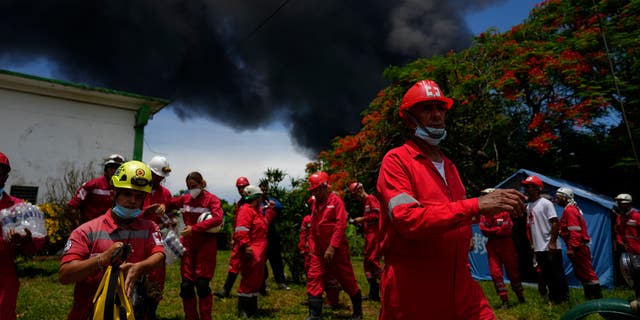 Các thành viên của Hội Chữ thập đỏ Cuba chuẩn bị di chuyển đến Căn cứ Siêu nhân viên Matanzas, khi các nhân viên cứu hỏa làm việc để dập lửa bùng phát trong một cơn giông bão đêm trước, ở Matazanas, Cuba, Thứ Bảy, ngày 6 tháng 8 năm 2022.