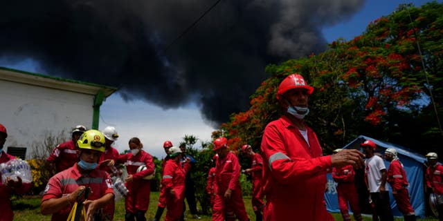 Miembros de la Cruz Roja Cubana se preparan para ser transportados a la base de superpetroleros de Matanzas, donde los bomberos trabajan para apagar un incendio que comenzó durante una tormenta eléctrica la noche anterior, en Matazanas, Cuba, el sábado 6 de agosto de 2022.