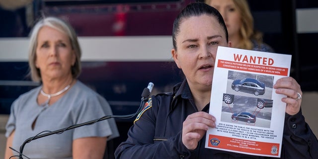 Albuquerque Police Deputy Chief of Investigations Cecily Barker holds a flyer with photos of a car wanted in connection with Muslim men murdered as Governor Michelle Lujan Grisham looks on in Albuquerque, New Mexico, Sunday, Aug. 7, 2022. 