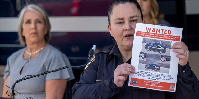 Albuquerque Police Deputy Chief of Investigations Cecily Barker holds a flyer with photos of a car wanted in connection with Muslim men murdered as Governor Michelle Lujan Grisham looks on in Albuquerque.