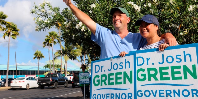 Hawaii Lt. Gov. Josh Green, left, and his wife, Jamie, greet passing cars while campaigning in Honolulu on Aug. 2, 2022.