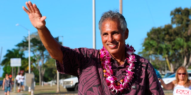 Former Hawaii Lt. Gov. James R. "Duke" Aiona waves at passing cars while campaigning in Kailua, Hawaii on Aug. 9, 2022. 