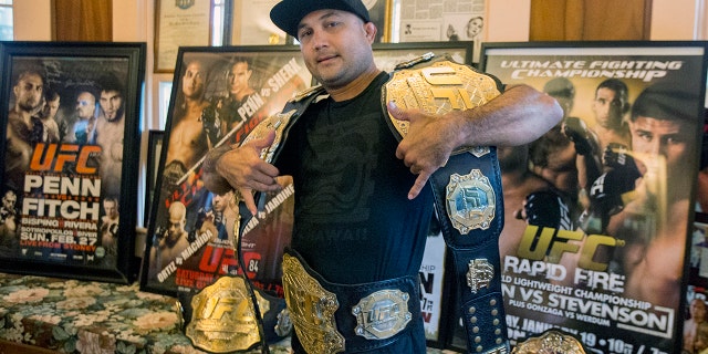 BJ Penn poses with all five of his UFC championship belts and several of his fight posters at his family's home on May 30, 2015, in Hilo, Hawaii.