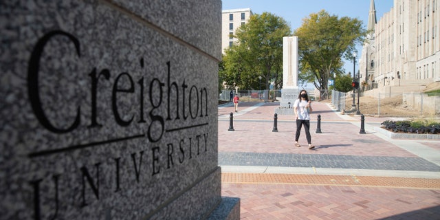 FILE - Students walk across 24th Street after the 24th Street dedication and ribbon cutting on the Creighton University campus in Omaha, Neb., Thursday, Sept.  24, 2020. The Nebraska Supreme Court on Friday, Aug. 12, 2022, has dismissed an appeal by a handful of Creighton University students seeking to be exempt from the school's COVID-19 vaccine mandate last year, arguing that getting the shots would violate their religious beliefs against abortion.  (Lily Smith/Omaha World-Herald via AP)