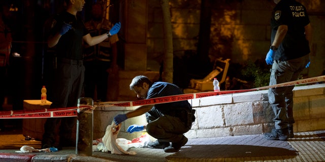 Israeli police crime scene investigators work at the scene of a shooting attack that wounded several Israelis near the Old City of Jerusalem, early Sunday, Aug. 14, 2022.