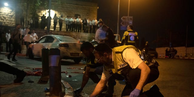 Volunteers with Zaka rescue service clean blood from the scene of a shooting attack that wounded several Israelis near the Old City of Jerusalem, early Sunday, Aug. 14, 2022.
