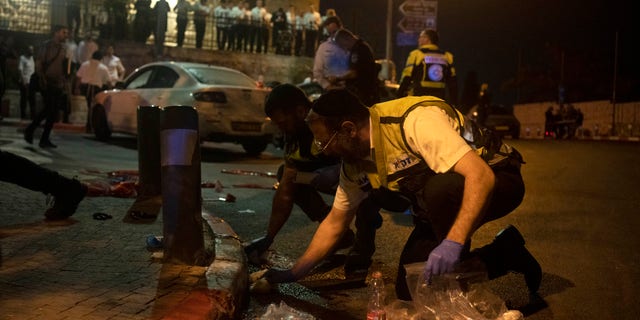 Volunteers with Zaka rescue service clean blood from the scene of a shooting attack that wounded several Israelis near the Old City of Jerusalem, early Sunday, Aug. 14, 2022.