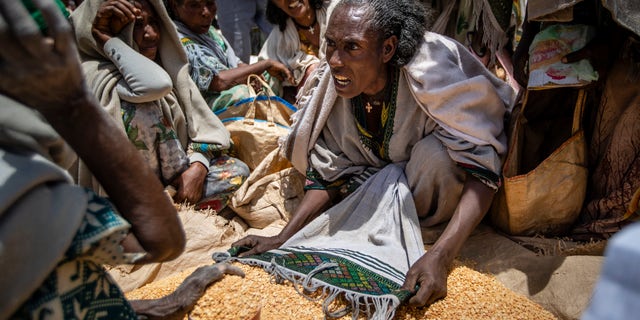 An Ethiopian woman discusses with other people the allocation of yellow peas after they were distributed by the Tigray Relief Society in the town of Agula, in the Tigray region of northern Ethiopia on May 8, 2021.