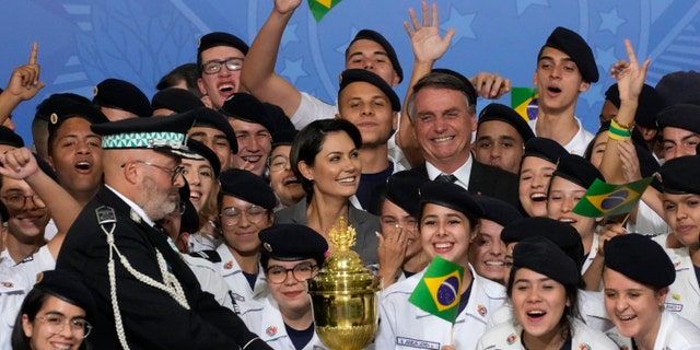 Brazil's President Jair Bolsonaro and his wife Michelle Bolsonaro, center, pose for photos with military cadets, next to the reliquary containing the heart of Brazil's former emperor Dom Pedro I, during a ceremony at the Planalto Presidential Palace in Brasilia, Brazil, Tuesday, Aug. 23, 2022. The heart arrived for display during the celebrations of Brazil's independence bicentennial on Sept. 7. (AP Photo/Eraldo Peres)