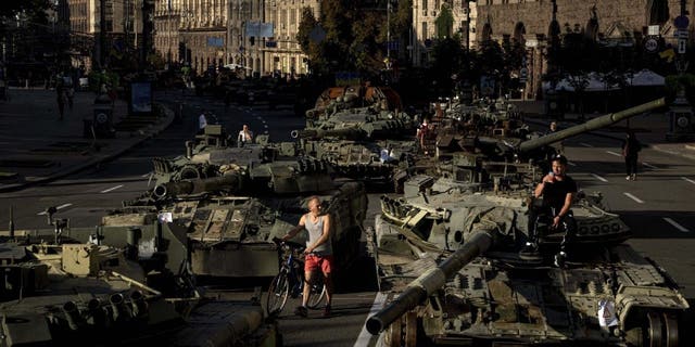 Люди ходят вокруг разбитой российской военной машины, установленной в центре Киева, Украина, среда, 24 августа 2022 года.