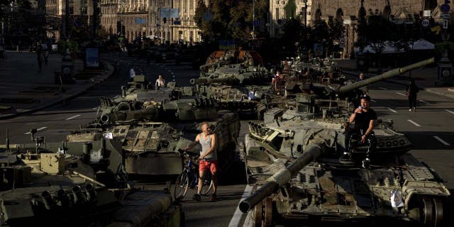 Люди ходят вокруг разбитой российской военной машины, установленной в центре Киева, Украина, среда, 24 августа 2022 года.