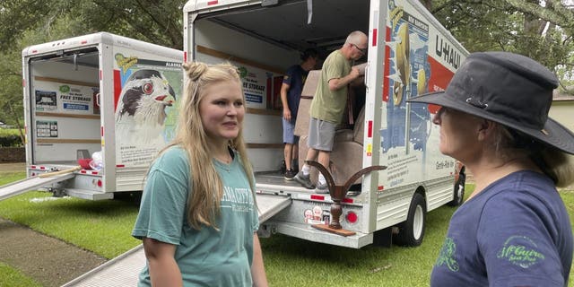 Medical student Emily Davis, left, speaks with her landlord Suzannah Thames on Friday, Aug. 26, 2022, as workers move furniture, appliances and other belongings out of a home Davis and her husband are renting in a flood-prone area of Jackson, Miss.