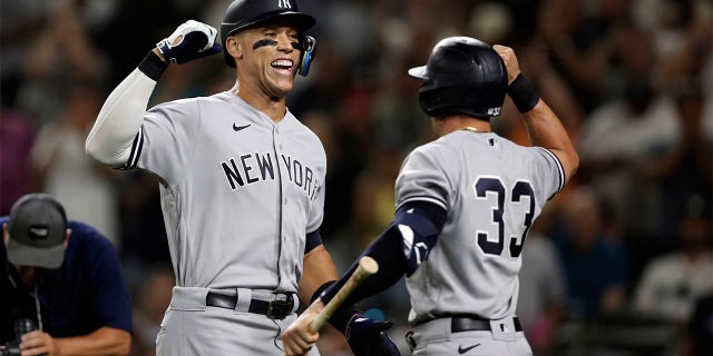 New York Yankees' Aaron Judge celebrates with Tim Locastro after hitting a solo home run on a pitch by Seattle Mariners' Ryan Borucci during the ninth inning of a baseball game, Monday, Aug. 8, 2022, in Seattle.