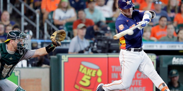 Houston Astros' Alex Bregman, right, connects for an RBI-double in front of Oakland Athletics catcher Stephen Vogt, left, during the seventh inning of a baseball game Sunday, Aug. 14, 2022, in Houston.