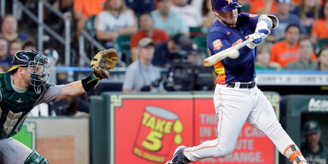 Houston Astros' Alex Bregman, right, connects for an RBI-double in front of Oakland Athletics catcher Stephen Vogt, left, during the seventh inning of a baseball game Sunday, Aug. 14, 2022, in Houston.