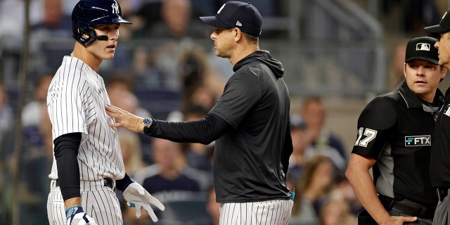 New York Yankees manager Aaron Boone, center, separates Anthony Rizzo, left, from home plate umpire D.J. Reyburn during the third inning against the Tampa Bay Rays at Yankee Stadium on Aug. 15, 2022, in New York.