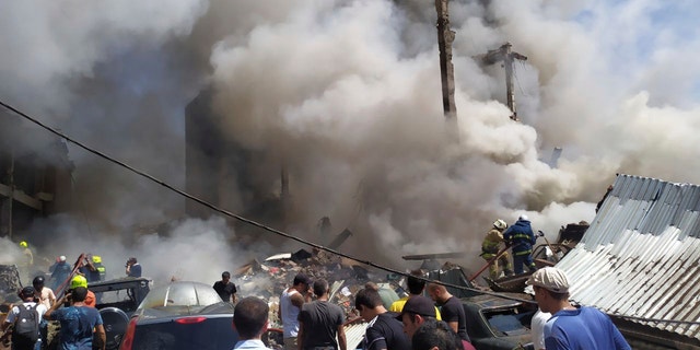 Smoke rises from Surmalu market about two kilometers (1.2 miles) south of the center Yerevan, Armenia, Sunday, Aug. 14, 2022. A strong explosion hit a large market in the capital of Armenia on Sunday, setting off a fire and reportedly trapping people under rubble. The Interfax news agency cited Armenia's emergency service as saying the explosion occurred in a building at the Surmalu market where fireworks were sold. (AP Photo/Daniel Bolshakov)