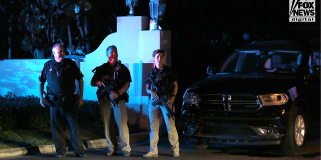 Three men with guns are seen standing outside the gates of Donald Trump's private Florida estate after the FBI raided the sprawling property allegedly looking for classified documents.