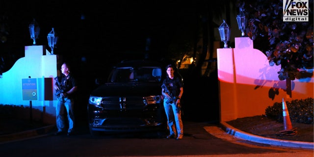 An armed guard stand outside Donald Trump's Florida Mar-a-Lago estate after 30 FBI agents tore through the property on Monday.