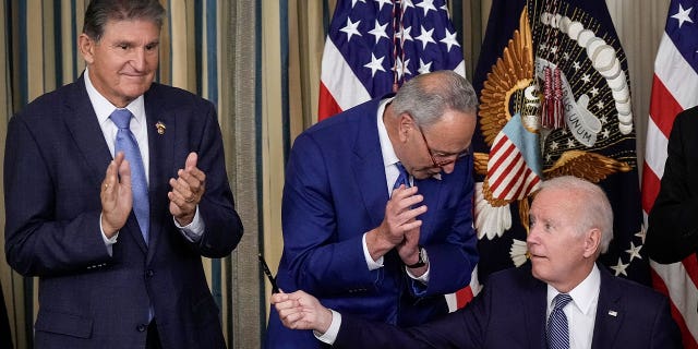 U.S. President Joe Biden (R) moves to give Sen. Joe Manchin (D-WV) (L) the pen he used to sign The Inflation Reduction Act with Senate Majority Leader Charles Schumer (D-NY) in the State Dining Room of the White House August 16, 2022 in Washington, DC.