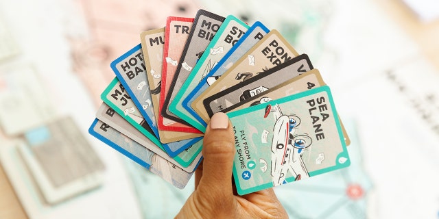 A USPS: The Great American Mail Race player holds playing cards.