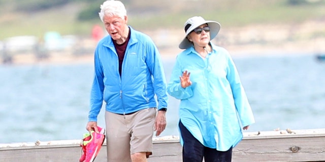 Former President Bill Clinton and former Secretary of State Hillary Clinton were spotted walking along the beach in the Hamptons on Thursday, Aug. 18. The Clintons were followed by their security as daughter Chelsea was spotted jogging nearby.