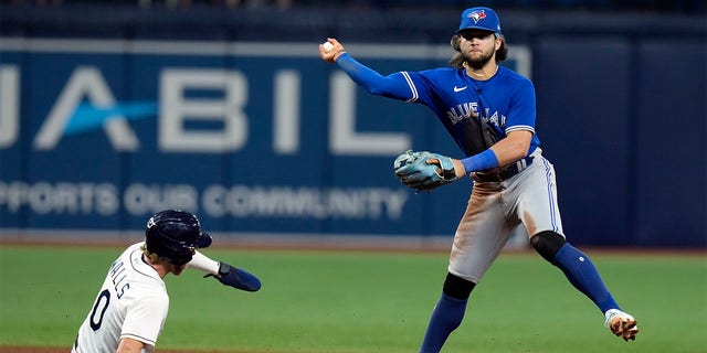 Toronto Blue Jays shortstop Bo Bichette forces Tampa Bay Rays' Taylor Walls (0) at second base and turns a double play on Randy Arozarena during the sixth inning of a baseball game Tuesday, Aug. 2, 2022, in St. Petersburg, Fla. 