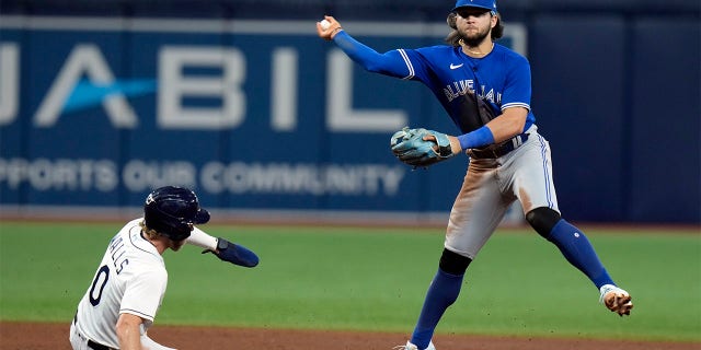 Toronto Blue Jays shortstop Bo Bichette forces Tampa Bay Rays' Taylor Walls (0) at second base and turns a double play on Randy Arozarena during the sixth inning of a baseball game Tuesday, Aug. 2, 2022, in St. Petersburg, Fla.
