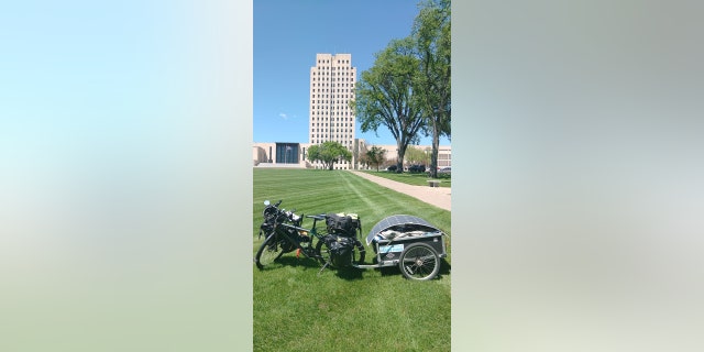 To help him ride faster, Barnes decided to winnow down his belongings. His bike and trailer are pictured at the North Dakota capitol building.