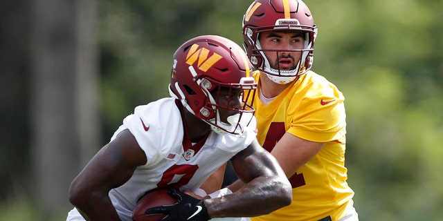 Washington Commanders quarterback Sam Howell hands the ball off to running back Brian Robinson during practice in Ashburn, Virginia, Aug. 22, 2022.