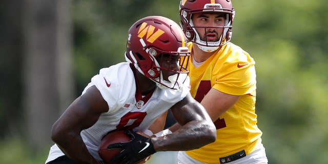 Washington Commanders quarterback Sam Howell hands the ball off to running back Brian Robinson during practice in Ashburn, Virginia, Aug. 22, 2022.