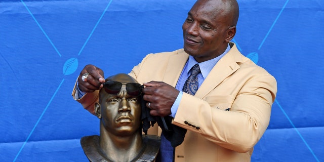 L'ex giocatore della NFL Bryant Young mette scherzosamente alcune sfumature sul suo busto durante una cerimonia di investitura presso la Pro Football Hall of Fame di Canton, Ohio, sabato 6 agosto 2022.