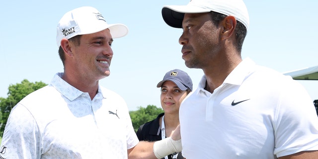 Bryson DeChambeau of the United States talks with Tiger Woods of the United States during a practice round prior to the start of the 2022 PGA Championship at Southern Hills Country Club on May 18, 2022 in Tulsa, Oklahoma.