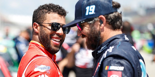 Bubba Wallace, left, and Martin Truex Jr. share a laugh on the grid during practice for the FireKeepers Casino 400 at Michigan International Speedway, Aug. 6, 2022, in Brooklyn, Michigan.