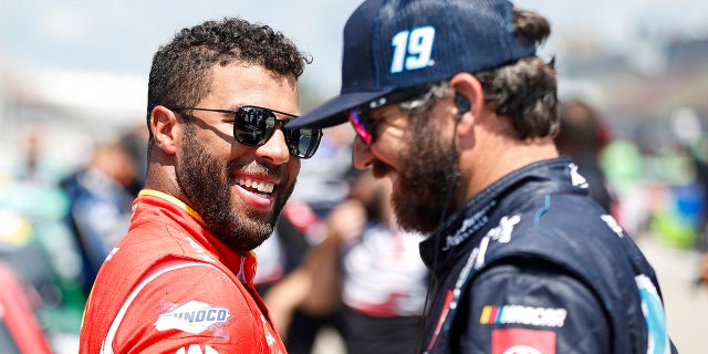 Bubba Wallace, left, and Martin Truex Jr. share a laugh on the grid during practice for the FireKeepers Casino 400 at Michigan International Speedway, Aug. 6, 2022, in Brooklyn, Michigan.