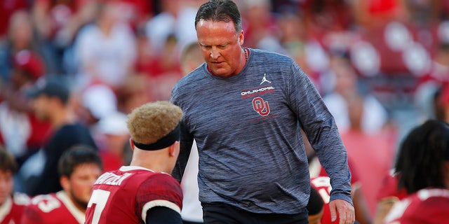 Oklahoma Sooners offensive coordinator Cale Gundy greets quarterback Spencer Rattler, #7, before a game against the West Virginia Mountaineers at Gaylord Family Oklahoma Memorial Stadium on September 25, 2021 in Norman, Oklahoma.