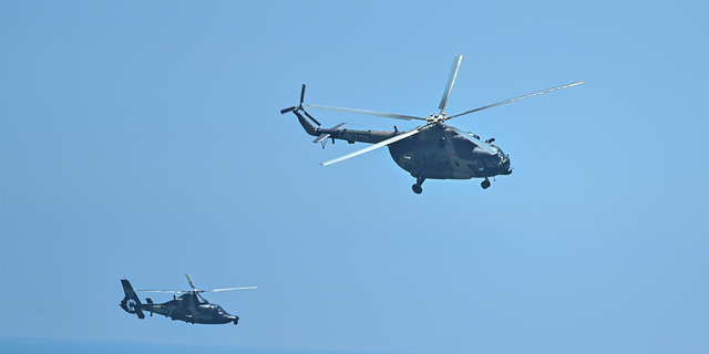 Chinese military helicopters fly past Pingtan island, one of mainland China's closest point from Taiwan, in Fujian province on August 4, 2022, ahead of massive military drills off Taiwan following US House Speaker Nancy Pelosi's visit to the self-ruled island. (Photo by Hector RETAMAL / AFP) (Photo by HECTOR RETAMAL/AFP via Getty Images)
