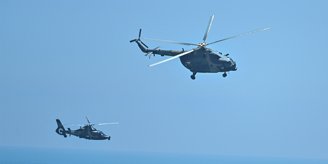 Chinese military helicopters fly past Pingtan island, one of mainland China's closest point from Taiwan, in Fujian province on August 4, 2022, ahead of massive military drills off Taiwan following US House Speaker Nancy Pelosi's visit to the self-ruled island. - China is due on August 4 to kick off its largest-ever military exercises encircling Taiwan, in a show of force straddling vital international shipping lanes following a visit to the self-ruled island by US House Speaker Nancy Pelosi. (Photo by Hector RETAMAL / AFP) (Photo by HECTOR RETAMAL/AFP via Getty Images)