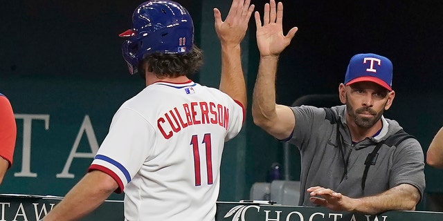 Texas Rangers' Charlie Culberson (11) gets a high-five from manager Chris Woodward during the fourth inning against the Seattle Mariners in Arlington, Texas, on Aug. 13, 2022.