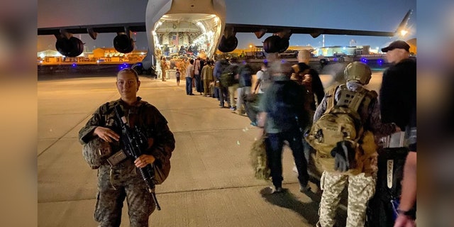 Gee escorts evacuees onto a plane at Hamid Karzai International Airport on Aug.  22, 2021.