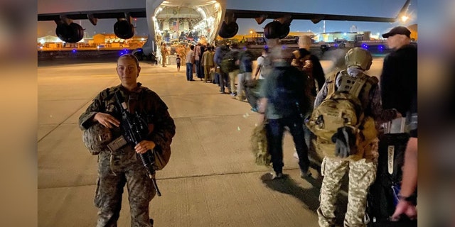 Gee escorts evacuees onto a plane at Hamid Karzai International Airport on Aug. 22, 2021.