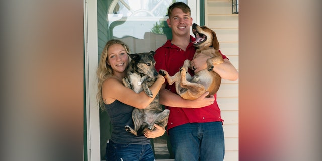Gee holds a dog alongside husband and fellow Marine, Jarod Gee.