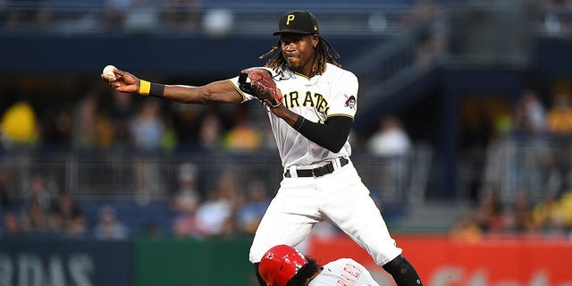 Oneil Cruz (15) of the Pittsburgh Pirates turns a double play in front of Jose Barrero (2) of the Cincinnati Reds during the fifth inning at PNC Park Aug. 19, 2022, in Pittsburgh.