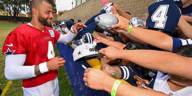 Dallas Cowboys quarterback Dak Prescott signs autographs for fans during opening day of NFL football training camp, Saturday, July 30, 2022, in Oxnard, Calif.