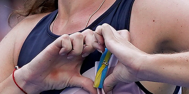 Daria Snigur, of Ukraine, makes a heart over her Ukrainian pin after upsetting Simona Halep, of Romania, during the first round of the US Open tennis championships, Monday, Aug. 29, 2022, in New York.